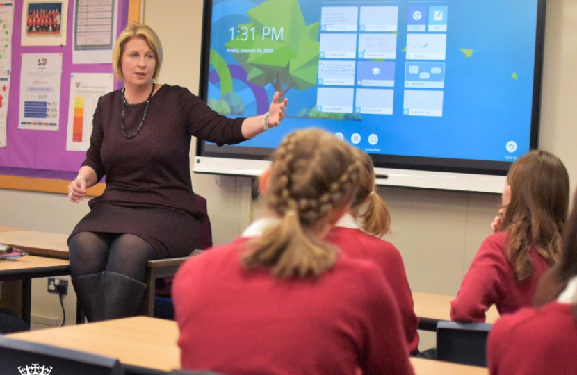 Katherine Fletcher sat on a desk, talking to pupils of Penwortham Girls' High School