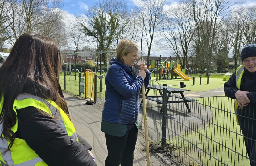 Katherine holding a garden tool and speaking to staff at a spring cleaning project