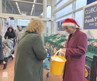 Katherine Fletcher with a charity bucket in her hand, speaking to someone in a supermarket.