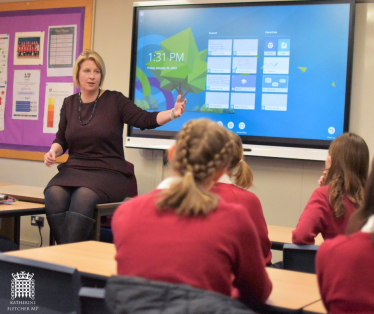 Katherine Fletcher sat on a desk, talking to pupils of Penwortham Girls' High School