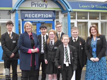 Katherine Fletcher stood outside Penwortham Priory Academy with a group of students and the vice principal.