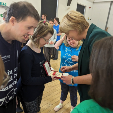 Jen showing Katherine and two other people her medal. 