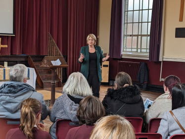 Katherine talking to a group of people at the front of Hutton Grammar school hall