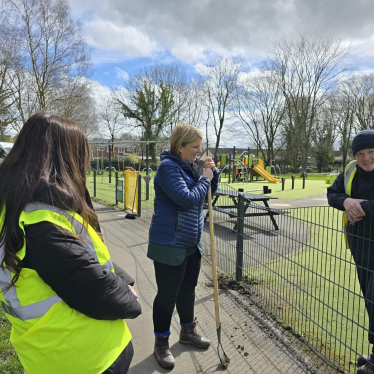 Katherine holding a garden tool and speaking to staff at a spring cleaning project